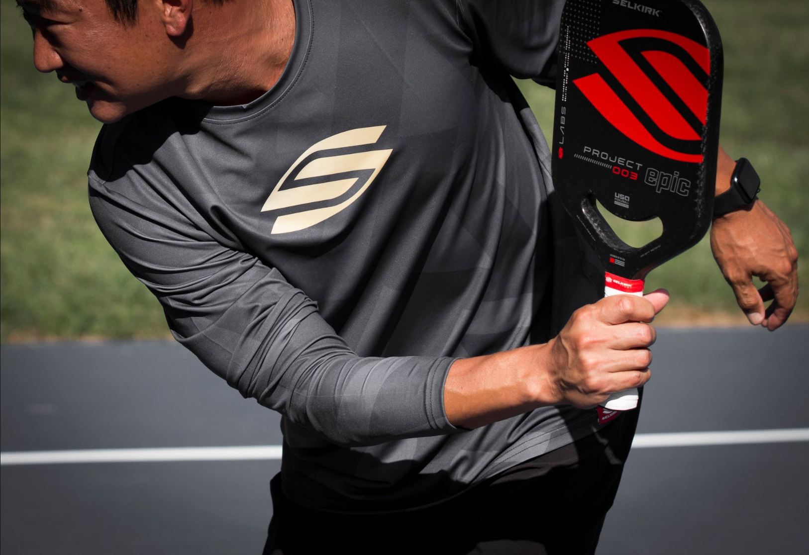 A player preparing to serve in pickleball, holding a paddle with a focused expression.