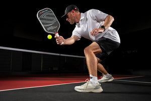 A player in pickleball shoes preparing to hit a ball with a paddle on a court.