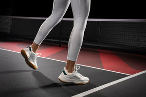 A person wearing pickleball shoes on a court surface, demonstrating footwear for the sport.