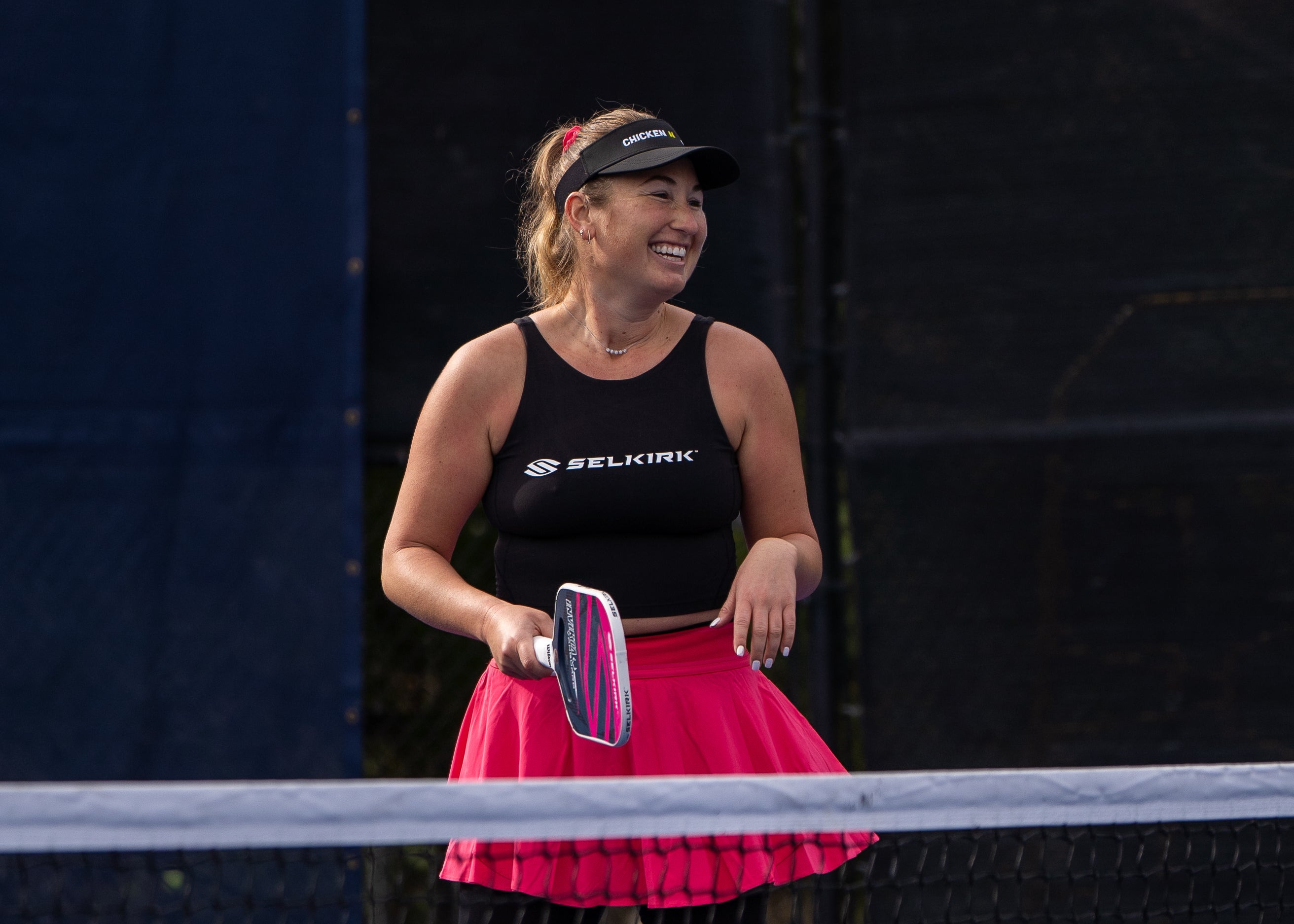 Lauren Stratman smiles on an outdoor pickleball court, holding a Selkirk Power Air paddle.