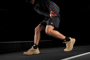 A player in beige pickleball shoes preparing to hit a ball with a paddle on a court.