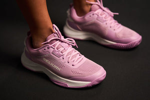Close-up of pink pickleball shoes on a dark background.