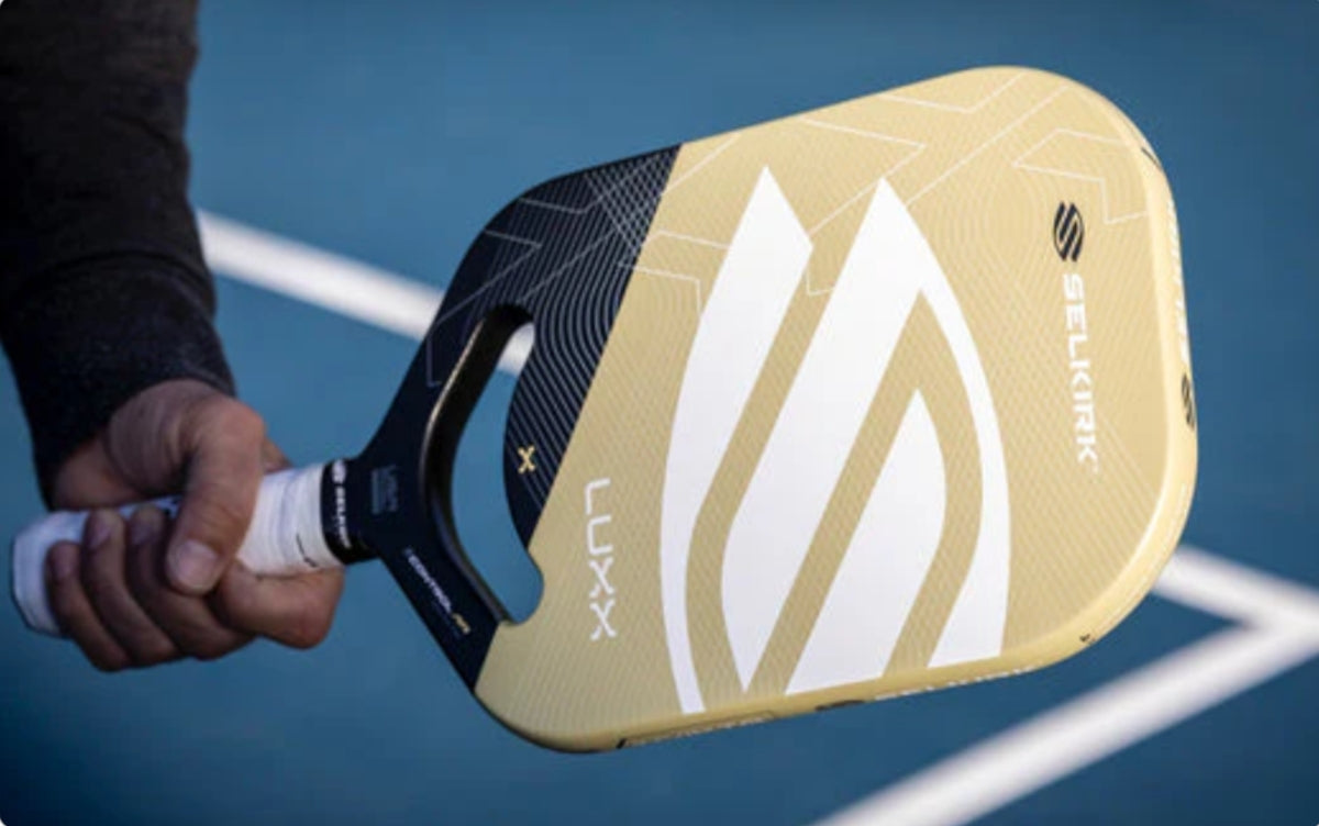 A person holding the LUXX Control Air pickleball paddle with a distinctive design.
