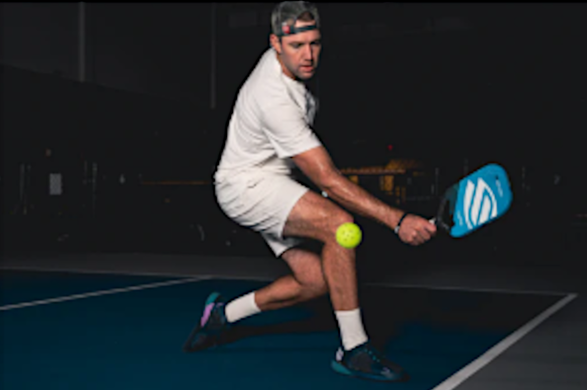 A player executing a backhand shot with a pickleball paddle on a court