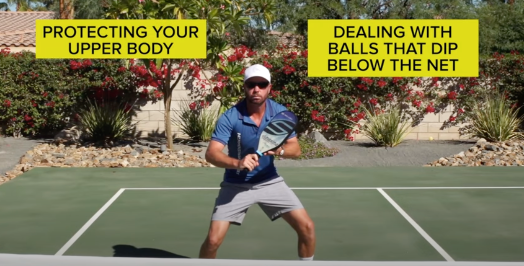 A man demonstrating how to hold a pickleball paddle, with text: 'Protecting Your Upper Body' and 'Dealing with Balls That Dip Below the Net'.