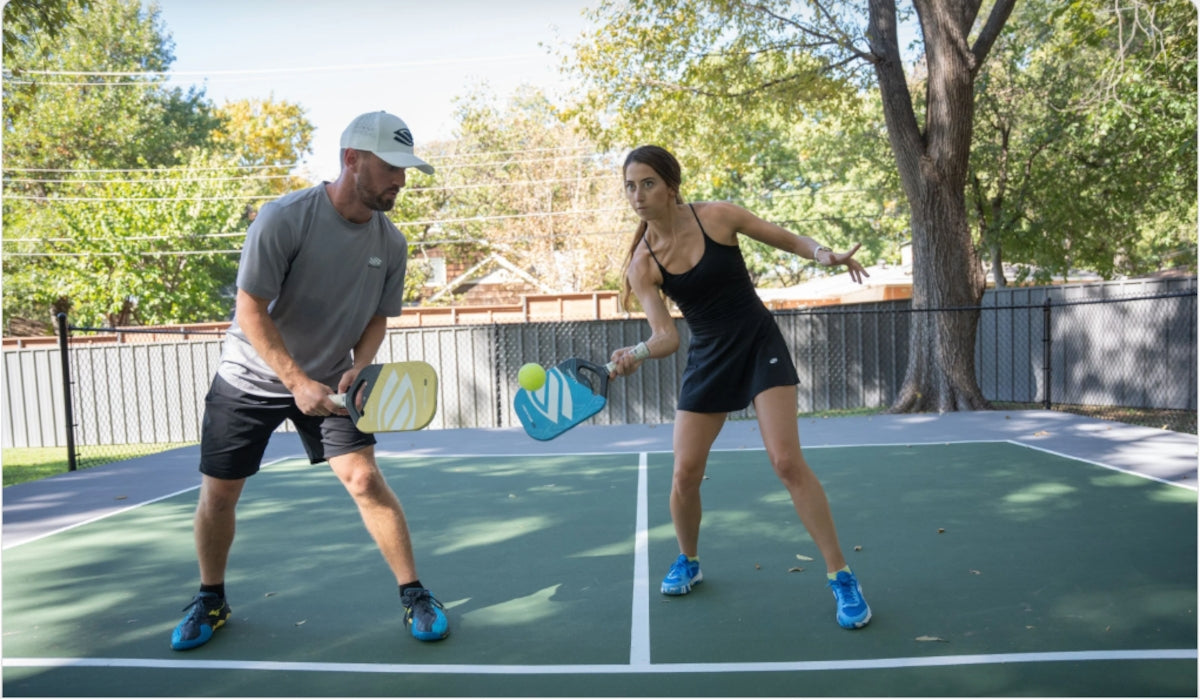 A couple playing pickleball on an outdoor court.