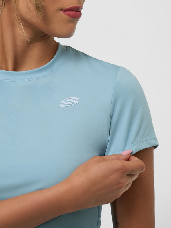 Model wearing a light blue women's training tee with a logo on the sleeve