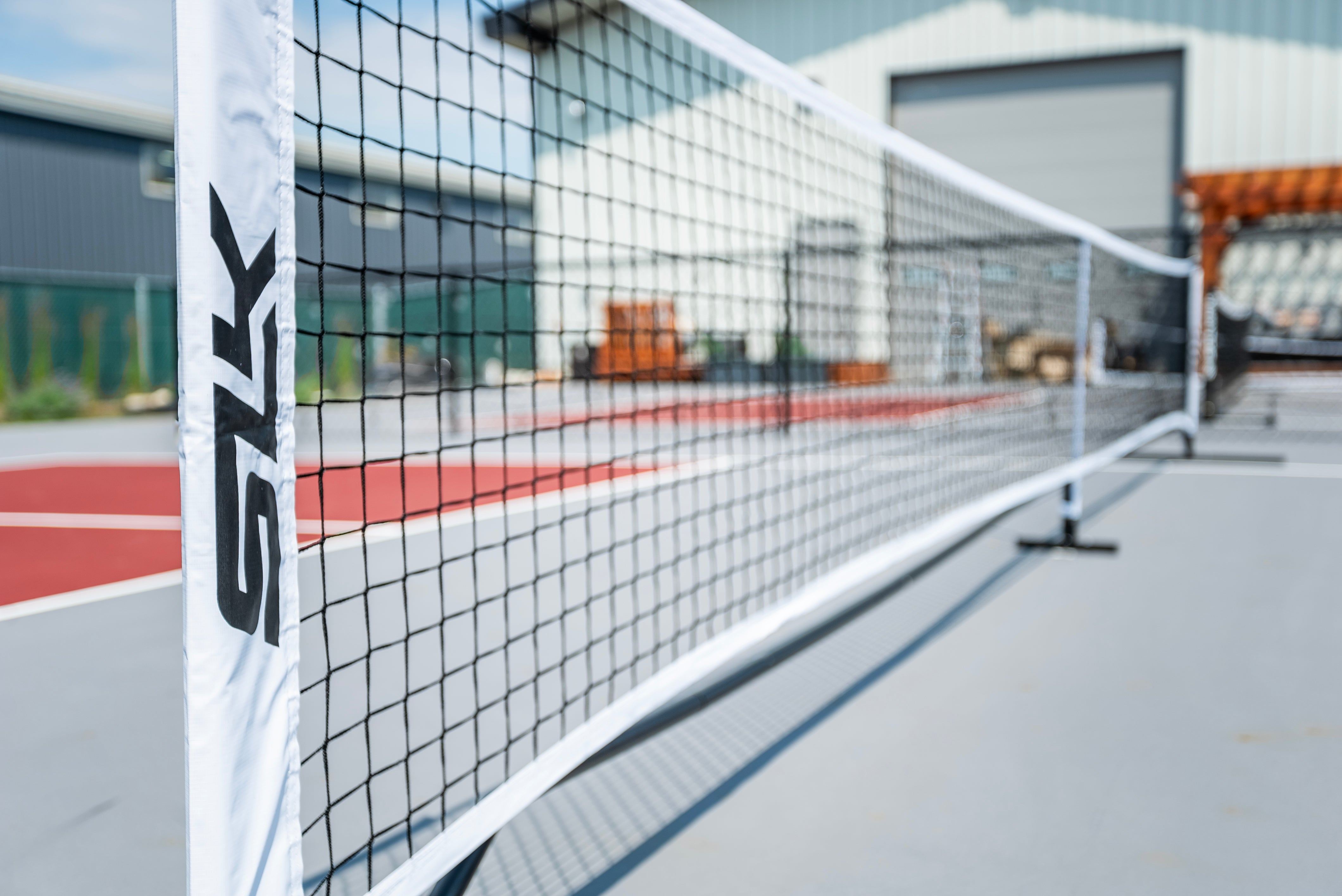 Portable pickleball net set up on a court, featuring a white net with 'SLK' branding.