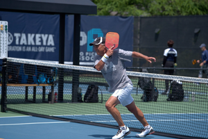 A player hitting a pickleball on a court with a paddle.