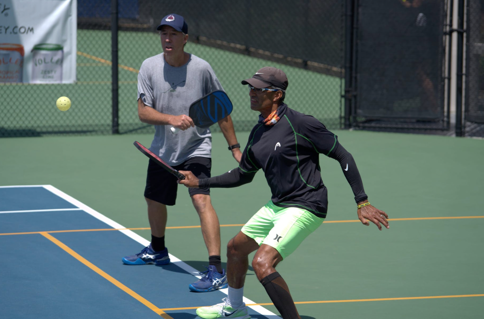 Two players engaged in a pickleball match on a court, one preparing to hit the ball.