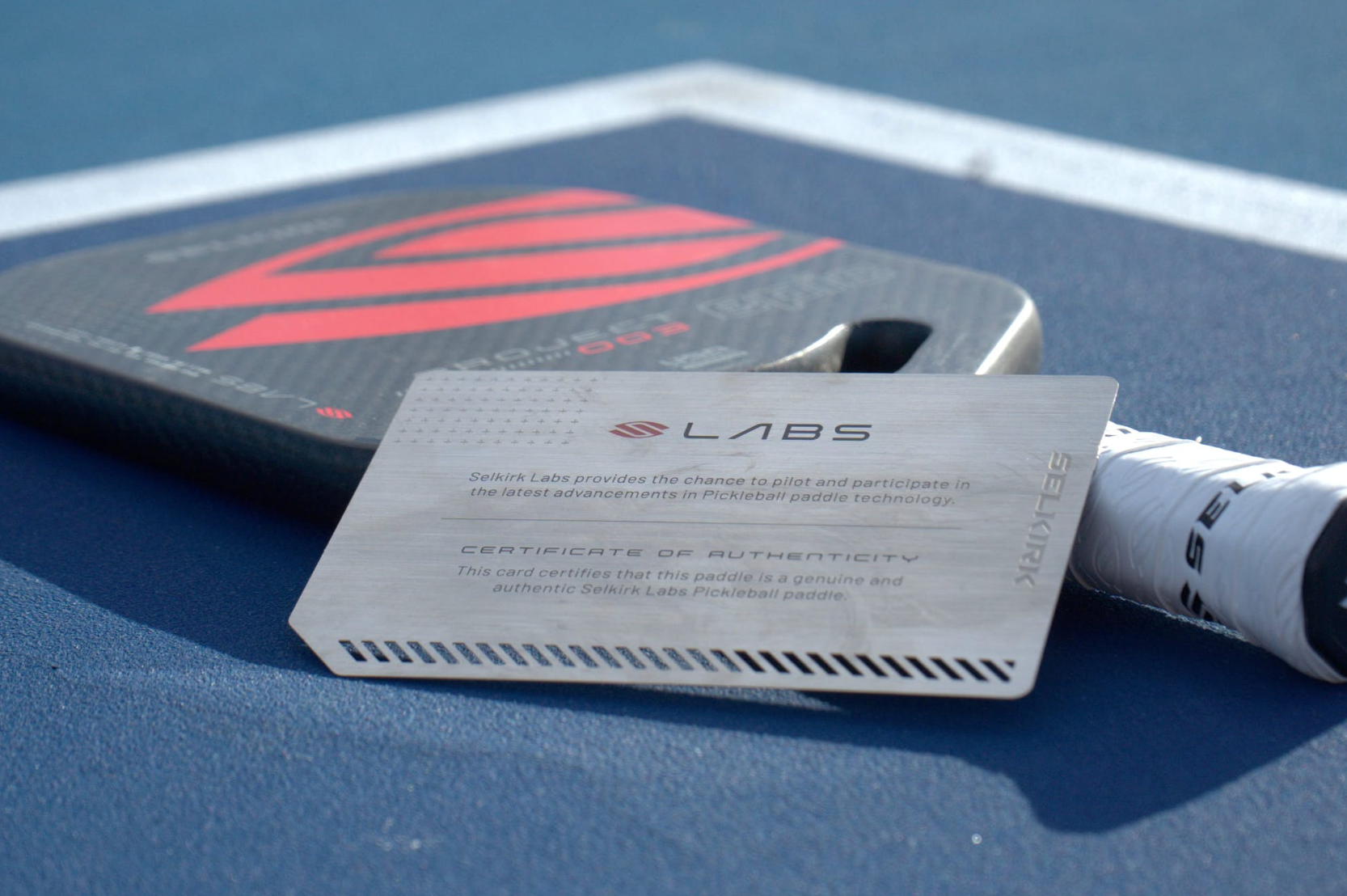 Selkirk Labs paddle with authenticity card on a blue court surface
