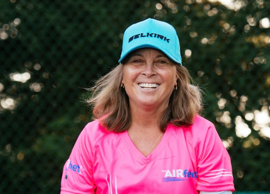 Chris Karges, a smiling woman wearing a pink shirt and blue cap, representing Selkirk.