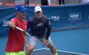 Two pickleball players on a court, one preparing to hit the ball.