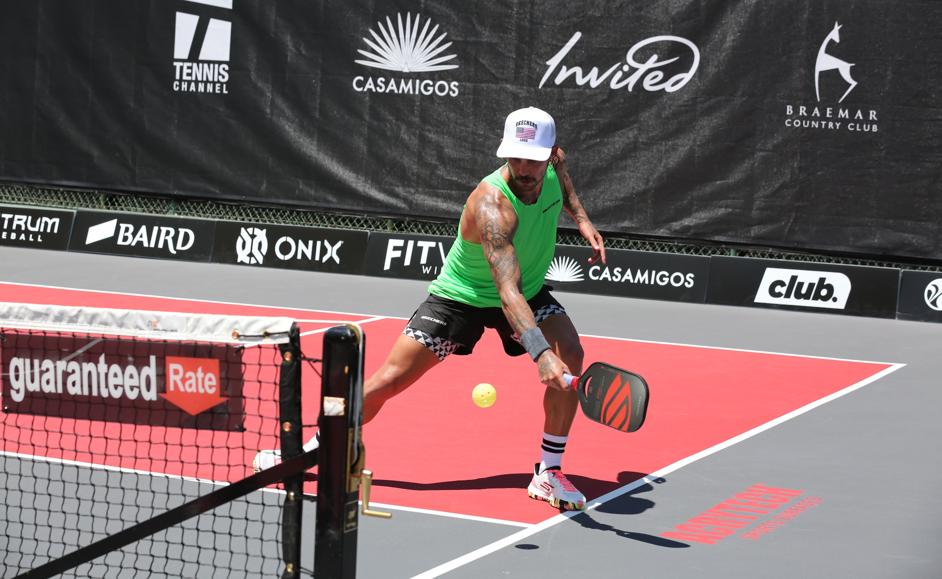 A player in a green tank top lunges to hit a pickleball during the Selkirk Labs Showdown.
