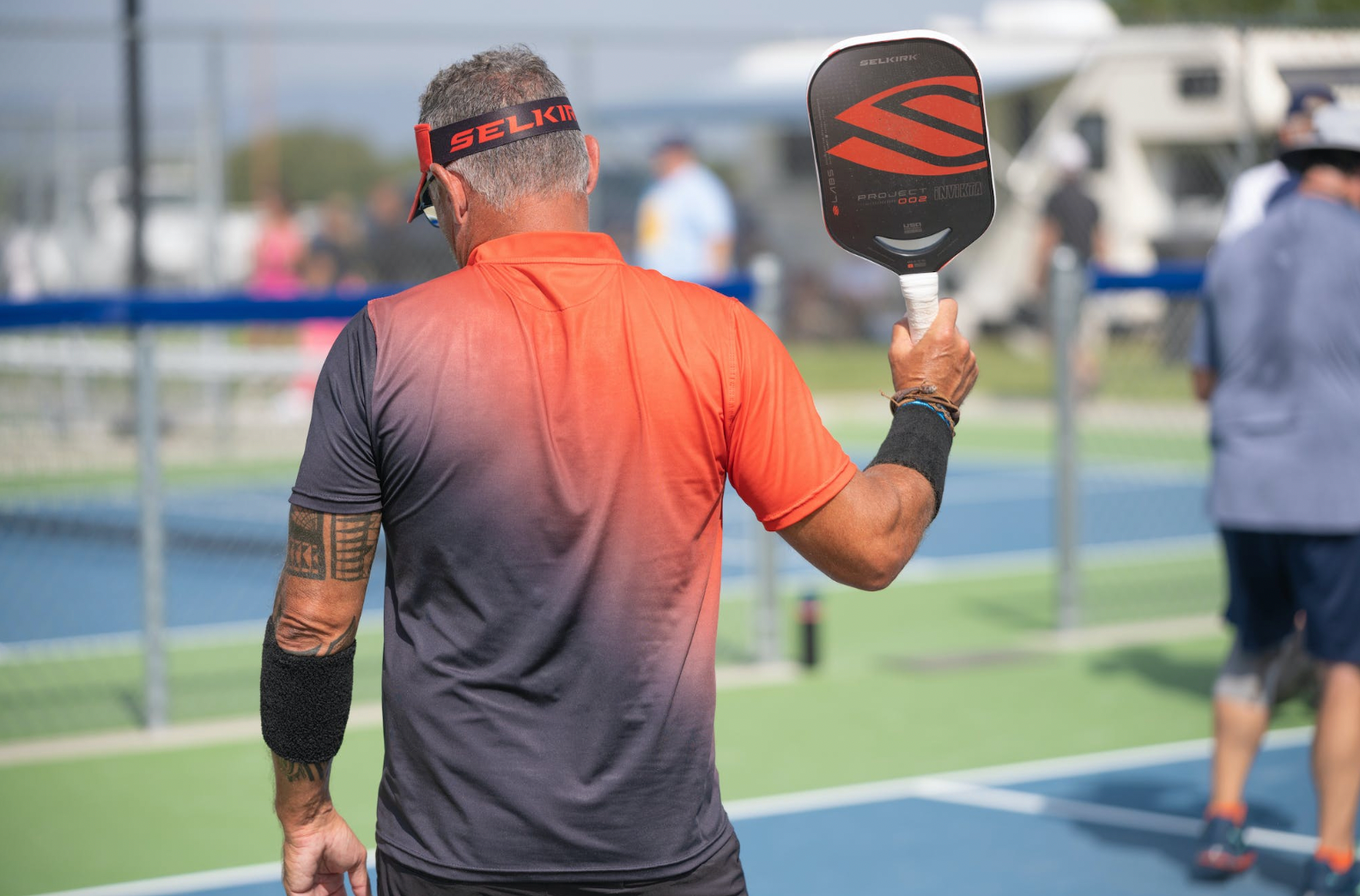 A player holding a pickleball paddle on a court.