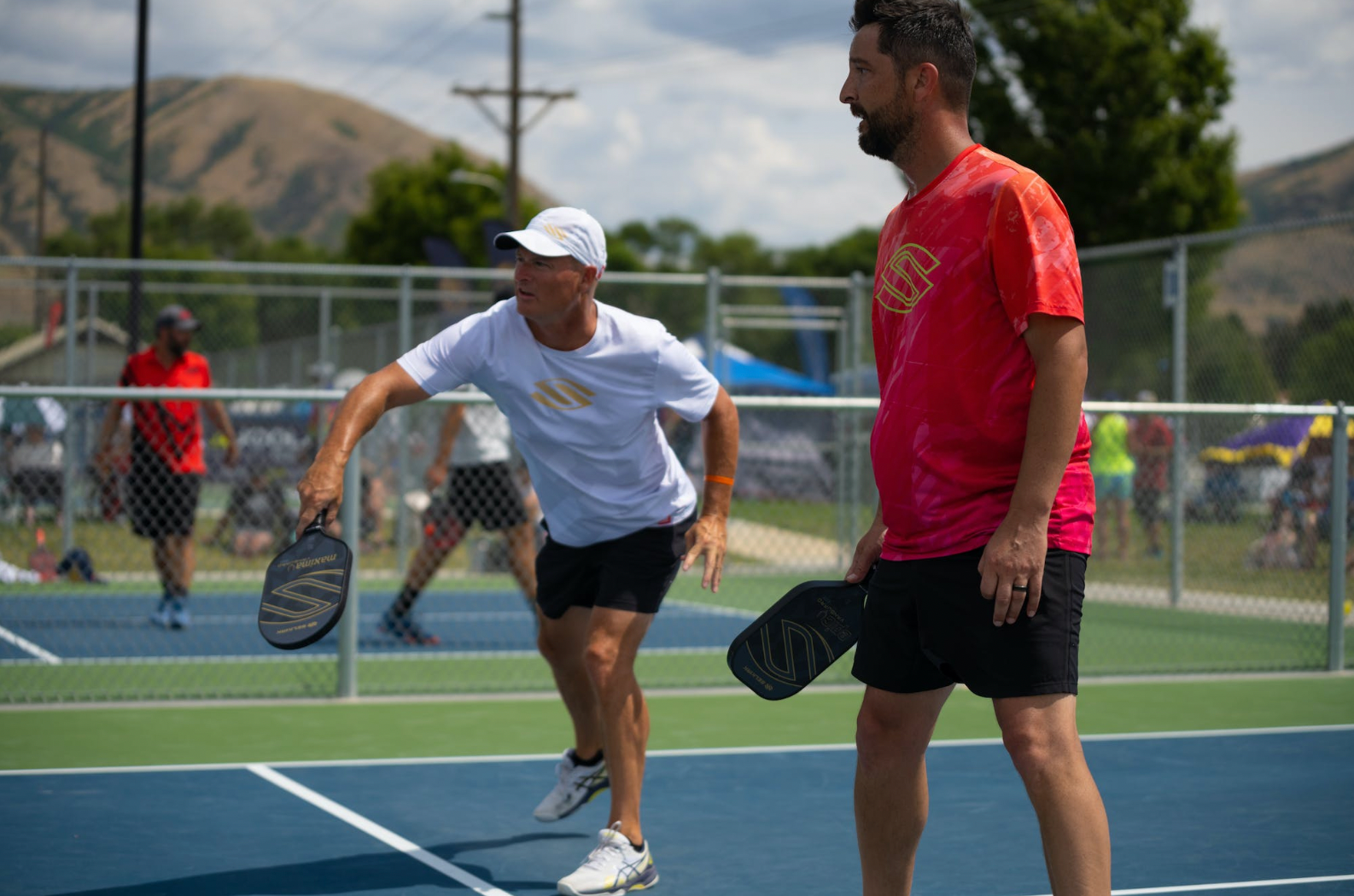 Two men playing pickleball, one preparing to serve, emphasizing core engagement.