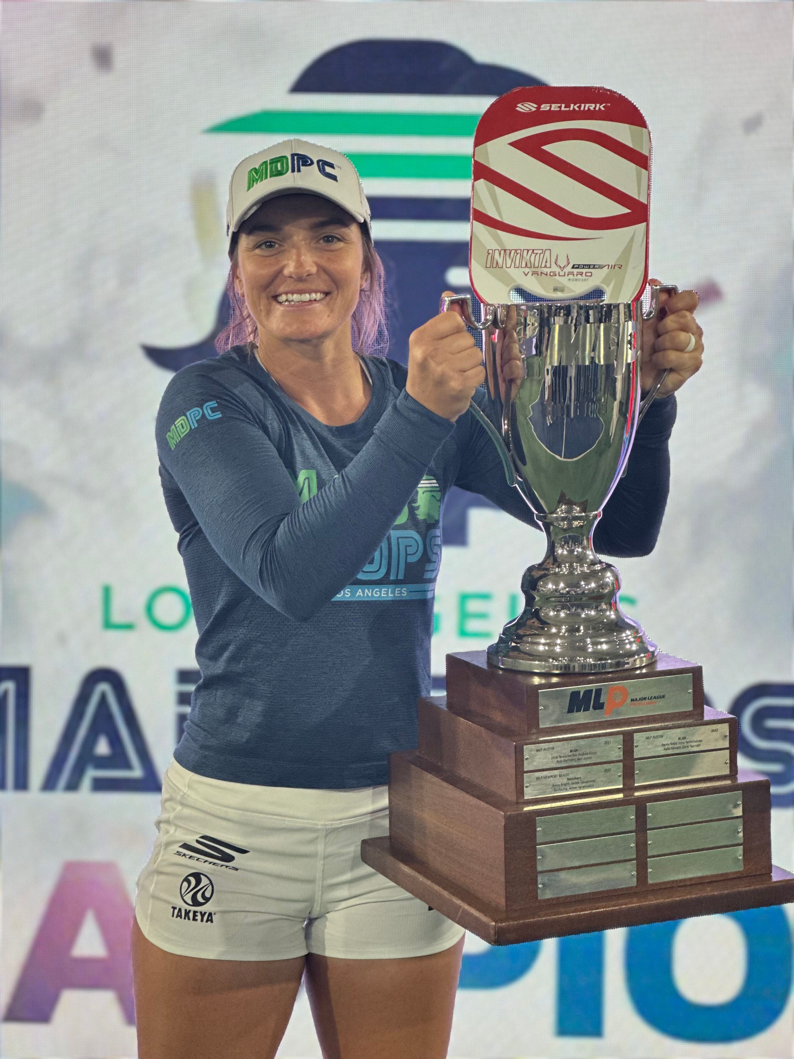 Female pickleball player holding the MLP championship trophy, celebrating victory.