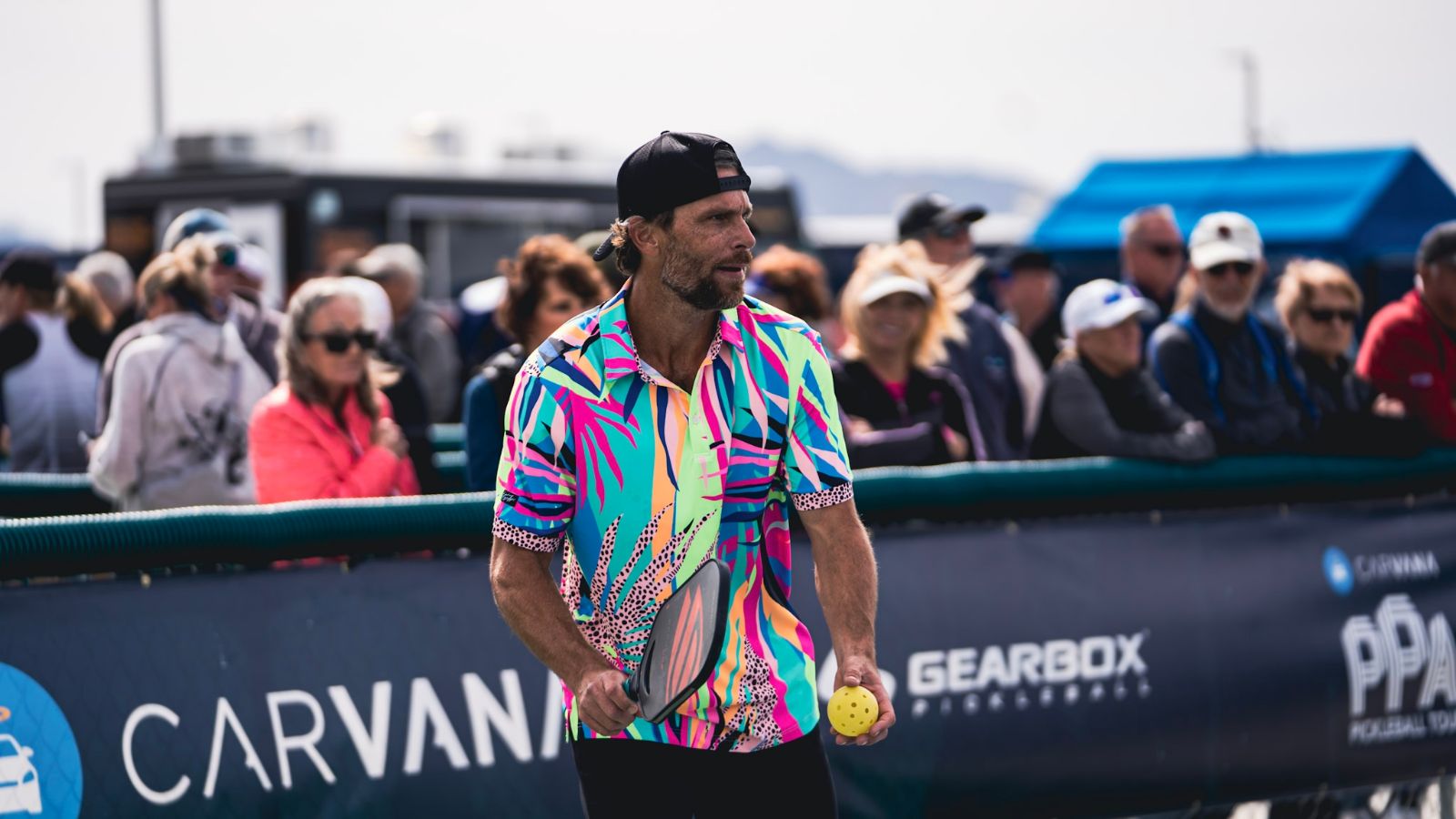 Male pickleball player in a colorful shirt preparing to serve during a tournament.