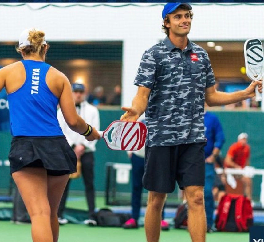 Catherine Parenteau and James Ignatowich celebrating on the court at the PPA Indoor National Championships, holding paddles.