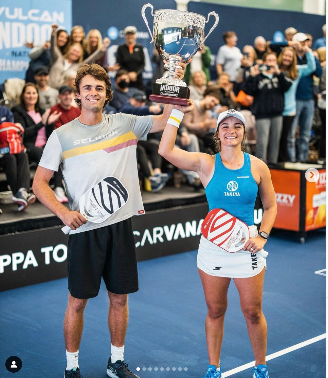 Two pickleball players celebrating with a trophy at the PPA tournament.
