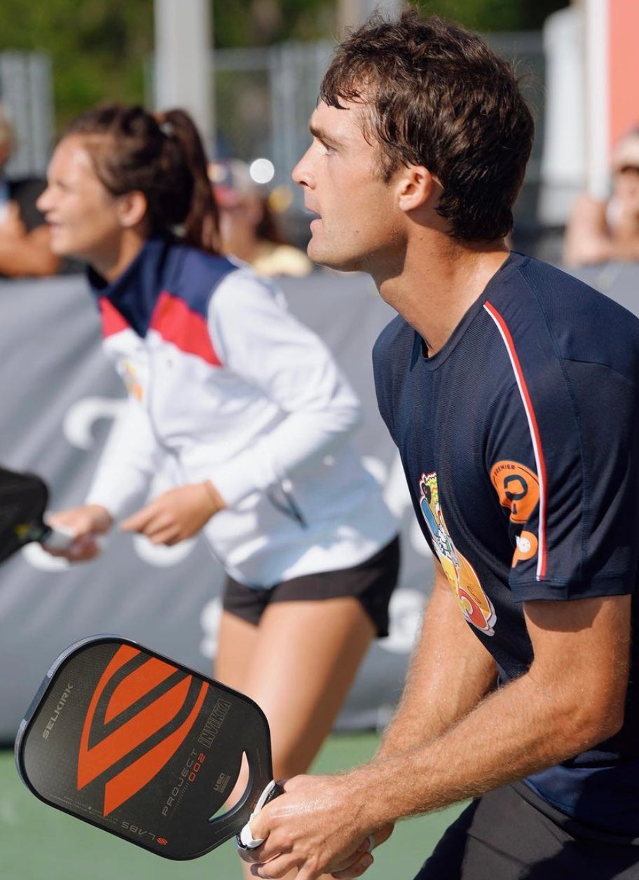 Two pickleball players in action during a match, one holding a paddle.
