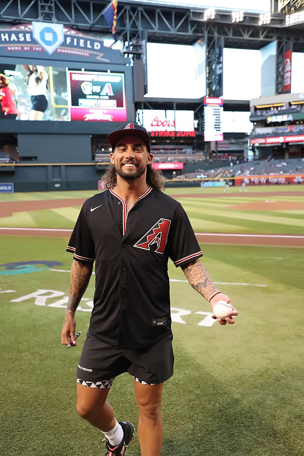 Tyson McGuffin walking on the field at Chase Field, holding a baseball