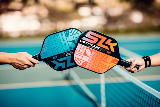Two pickleball paddles, one blue and one orange, held by players at a net.