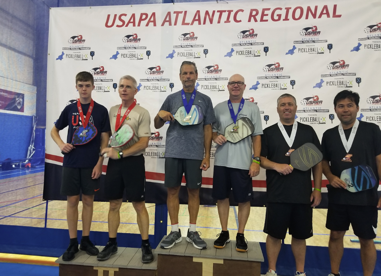 Robert R. and five other players at the USAPA Atlantic Regional tournament, holding paddles and medals.