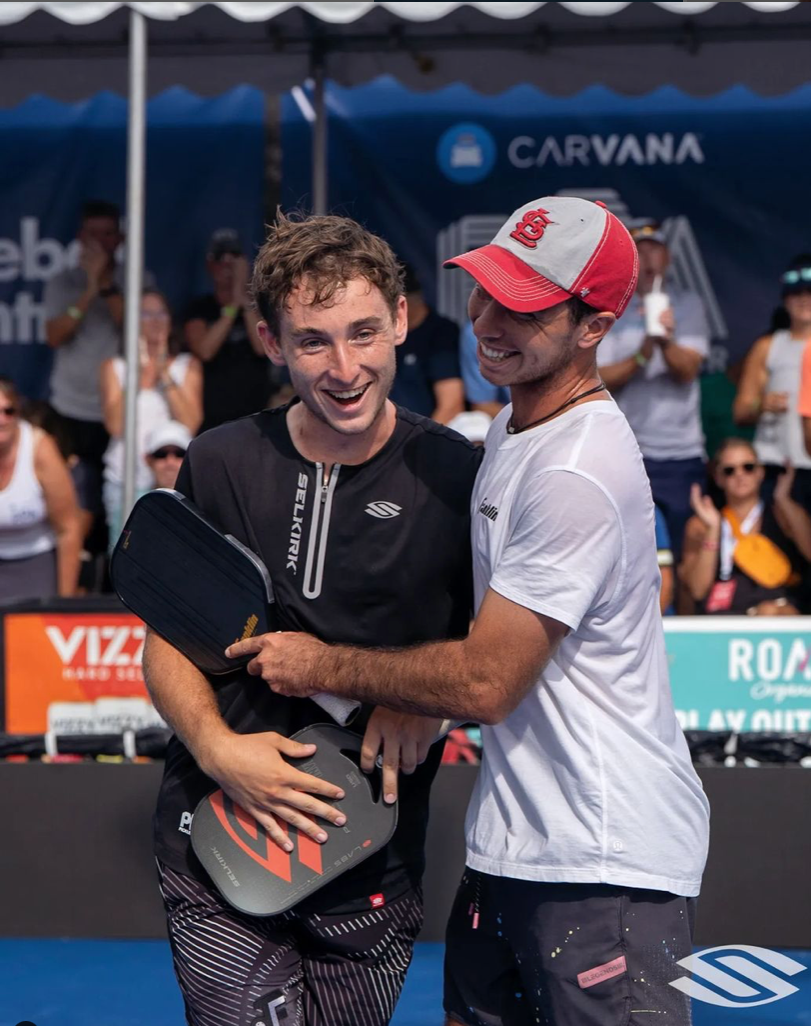 Two pickleball players celebrating after a match, smiling and embracing each other.