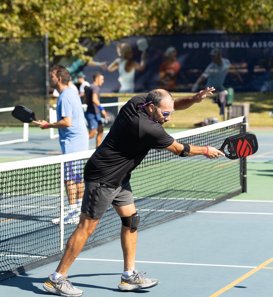 A player hitting a pickleball during a game on a court.
