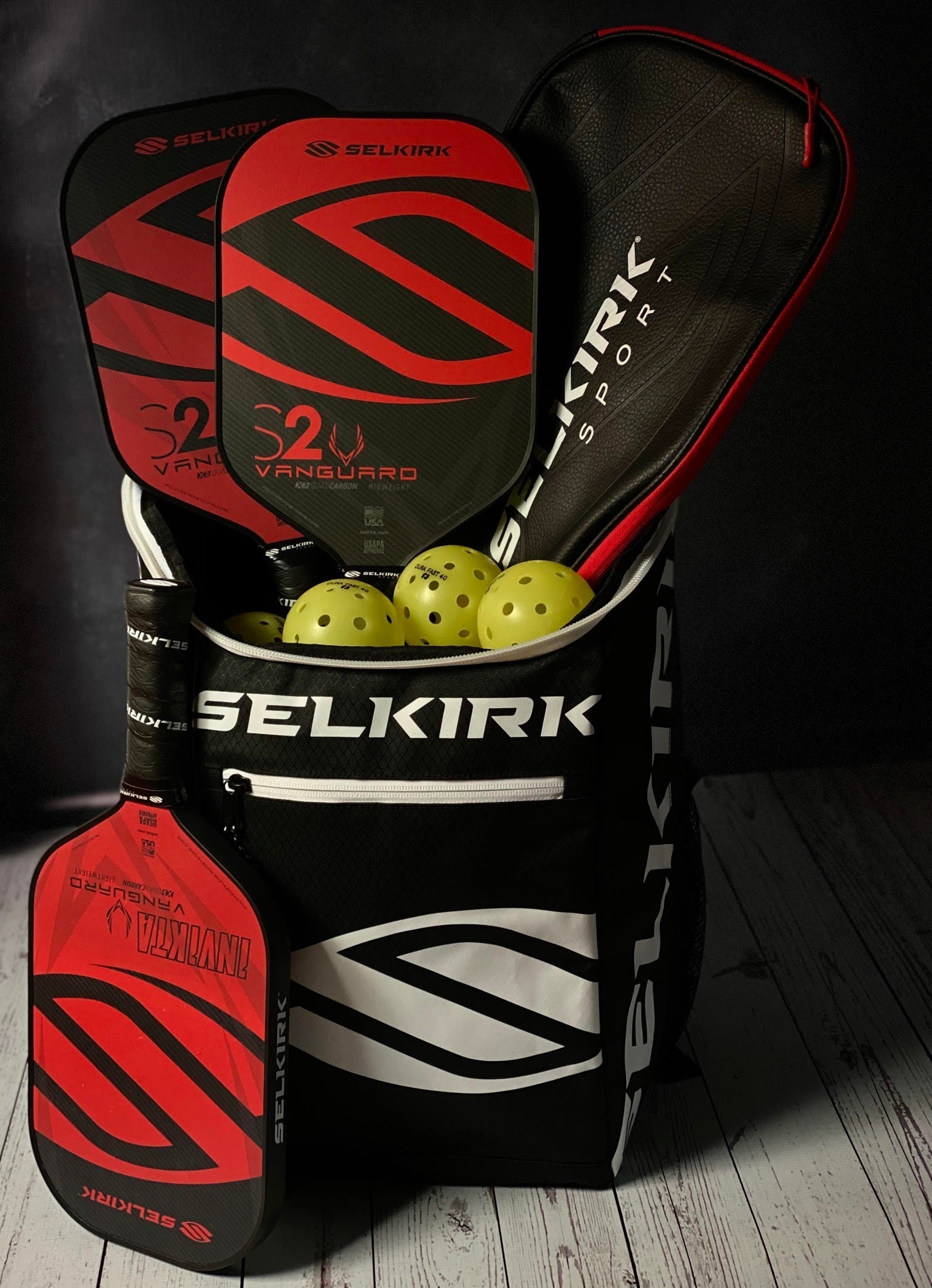 A bag containing red Selkirk pickleball paddles and yellow balls