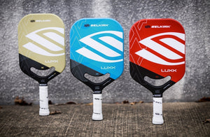 Three Selkirk pickleball paddles in different colors: beige, blue, and red, showcasing their designs.