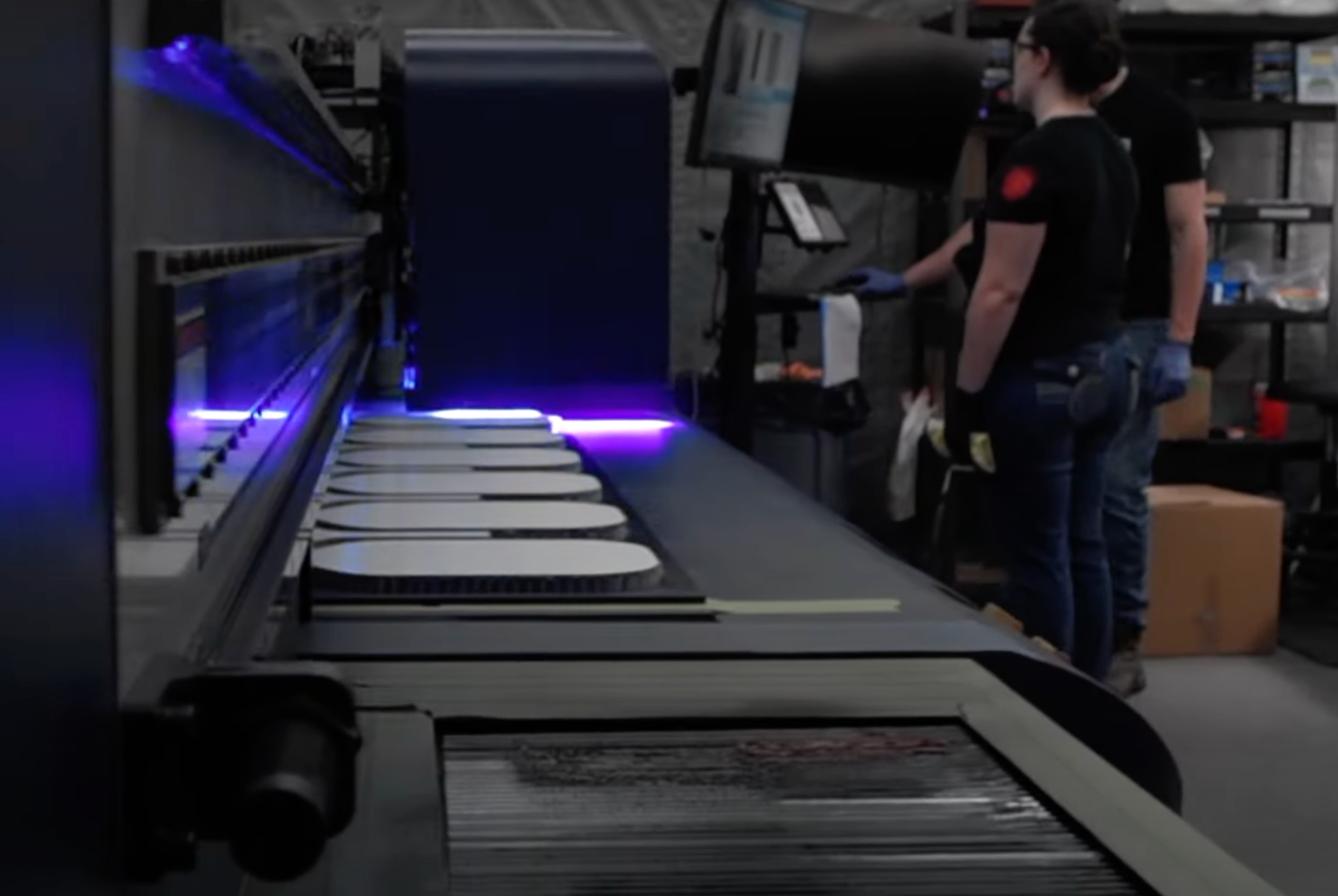 Workers operating machinery in a pickleball paddle manufacturing facility