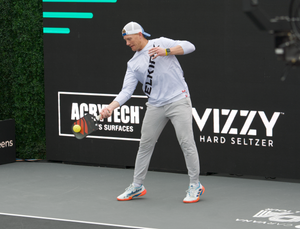 A pickleball player demonstrating a serve on the court.