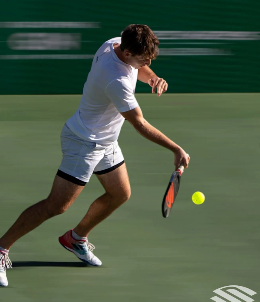 A male player hitting a pickleball with a paddle during a match.