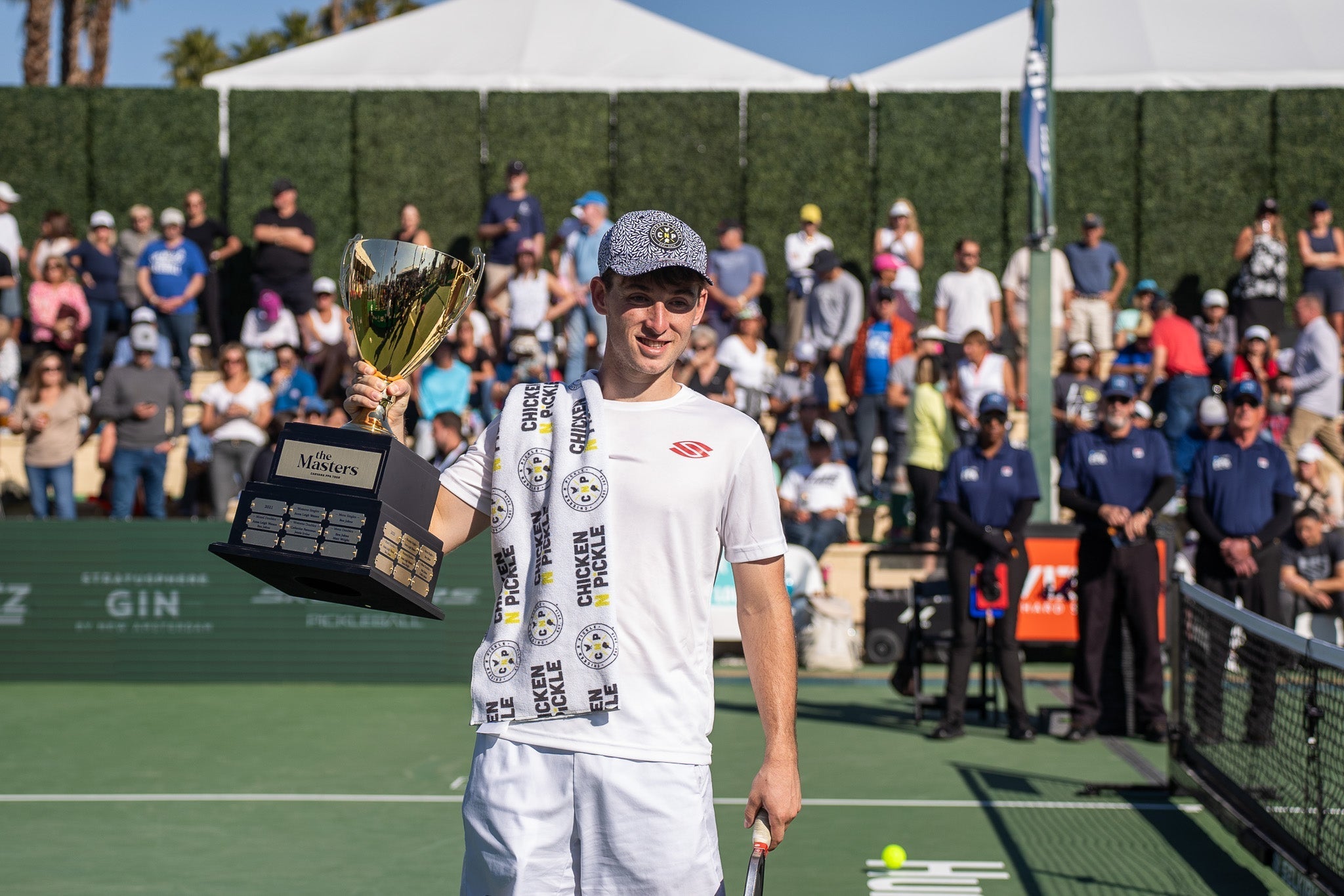 A player holding a trophy at the PPA Skechers Invitational, celebrating victory.