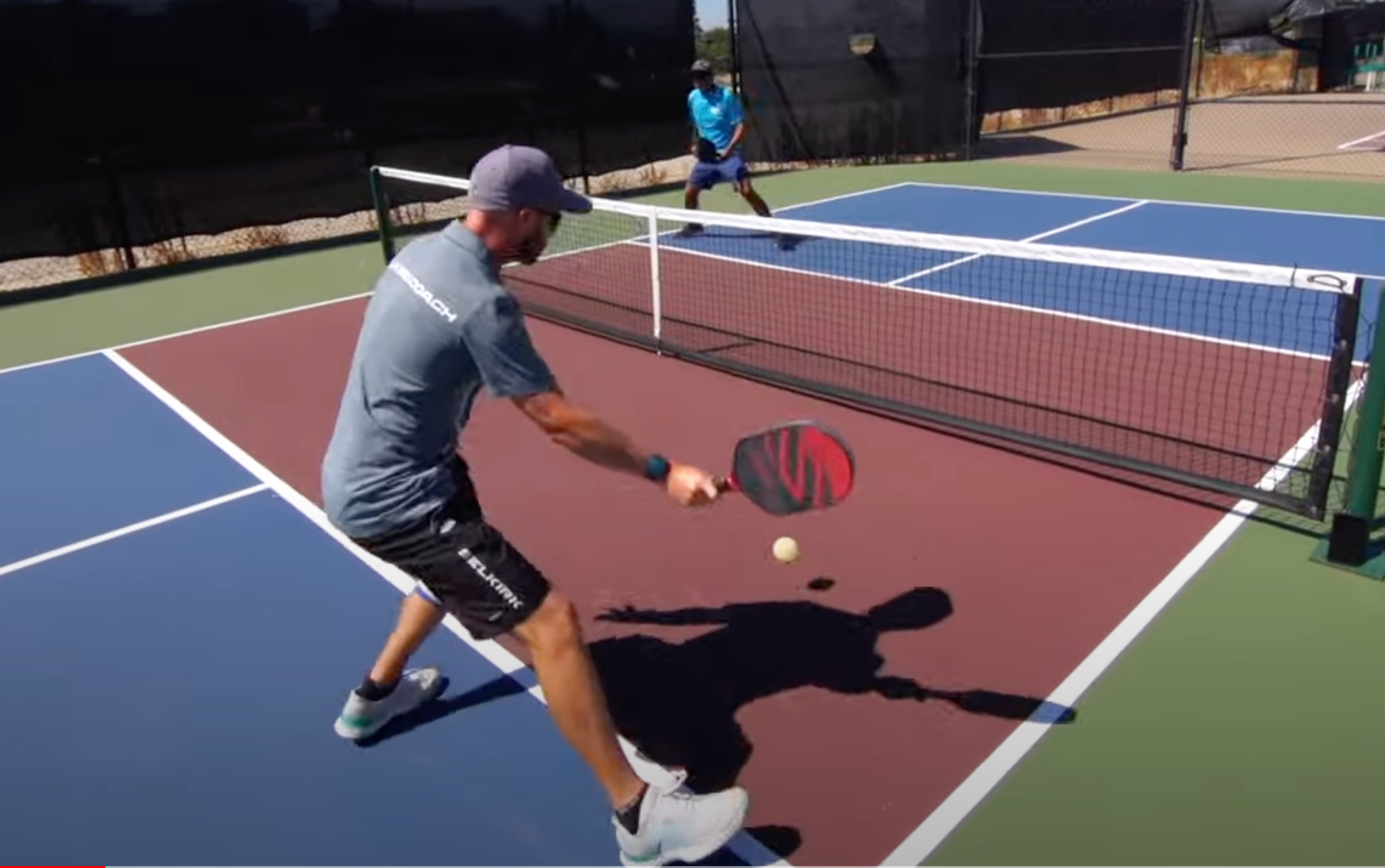 A player hitting a pickleball with a paddle while another player stands ready at the net.