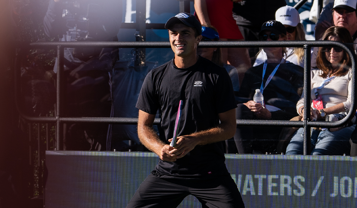 James Ignatowich smiling while preparing for a shot during a match, showcasing his paddle and athleticism.