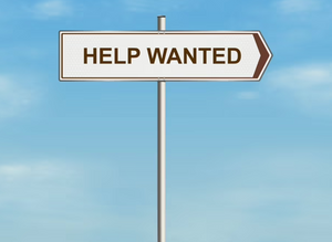 A sign that reads 'HELP WANTED' against a blue sky.