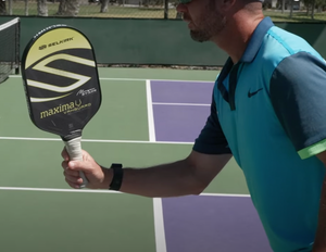 A player demonstrating proper paddle grip at the kitchen line in pickleball.