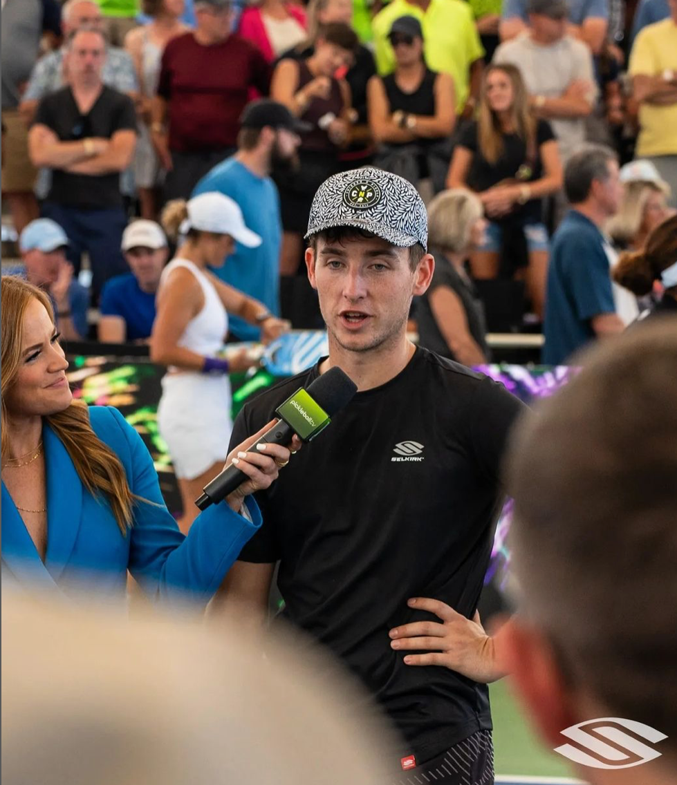 Ben Johns being interviewed after a match at the Skechers Invitational, with a crowd in the background.