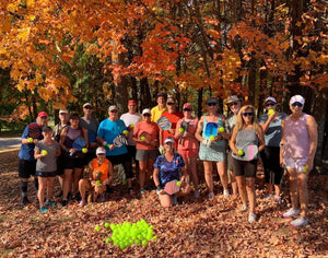 Group of pickleball players holding paddles and balls in a fall setting