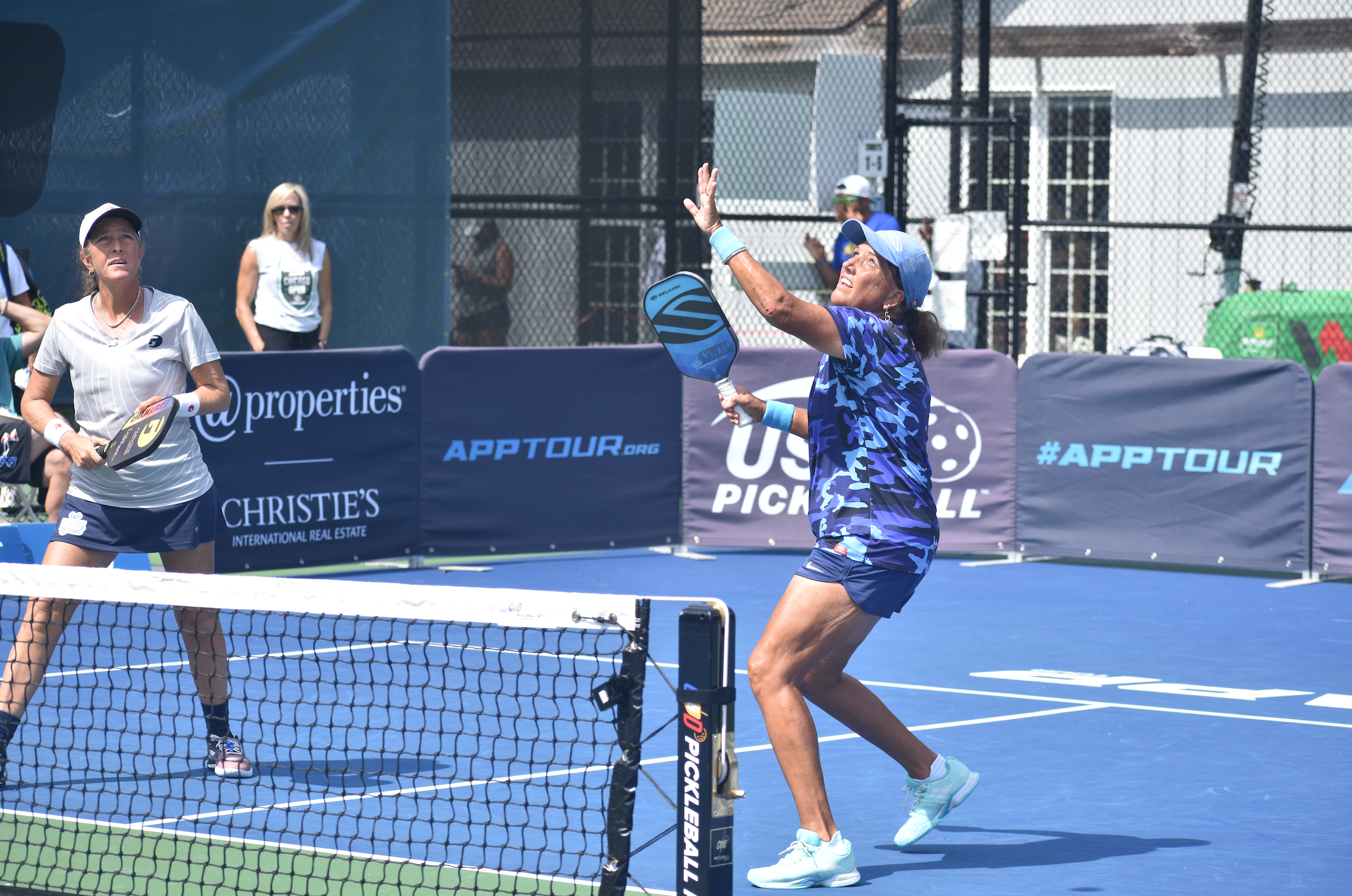 Two pickleball players competing on the court, one preparing to hit the ball.