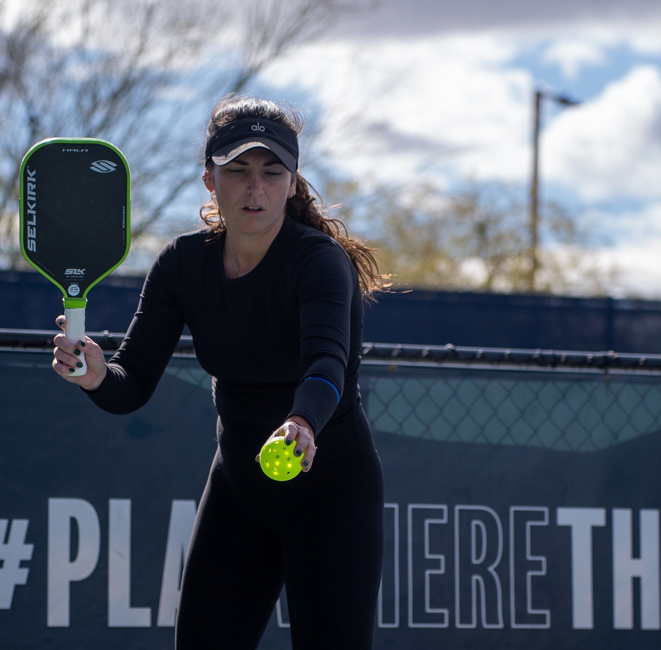 A player preparing to serve in pickleball, holding a paddle and ball.