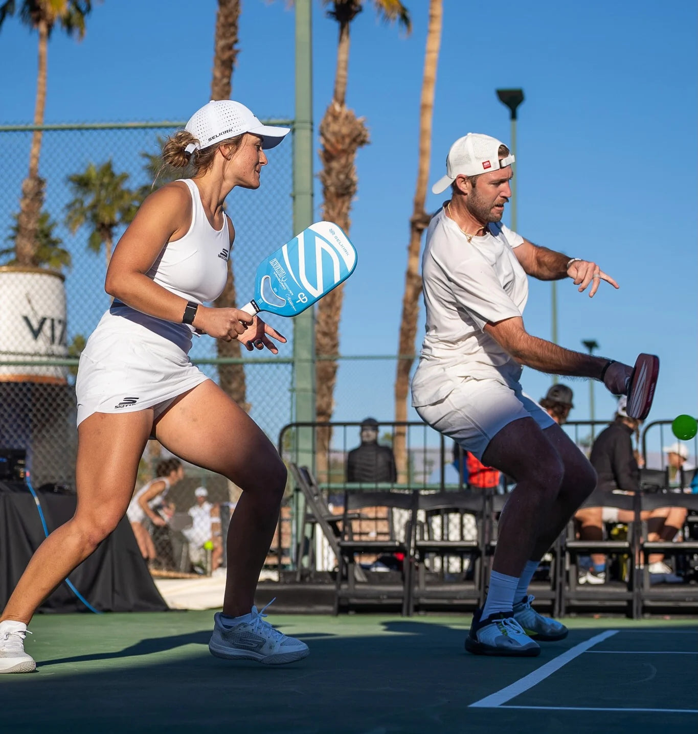 Two pickleball players in action, one preparing to hit the ball while the other is ready to receive.