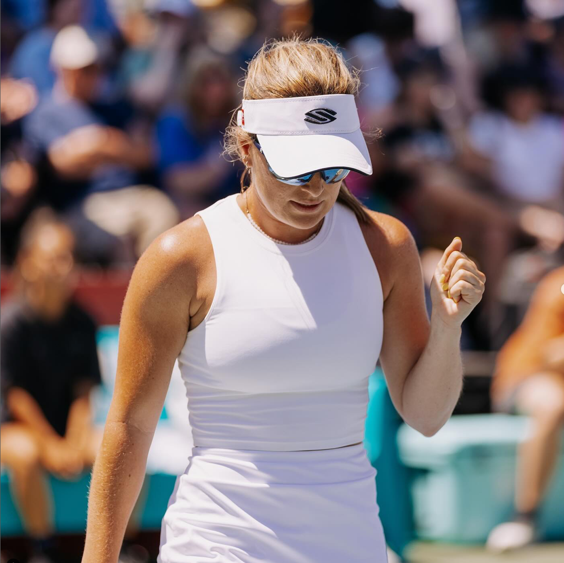 A female pickleball player in a white outfit celebrating a point during a match.