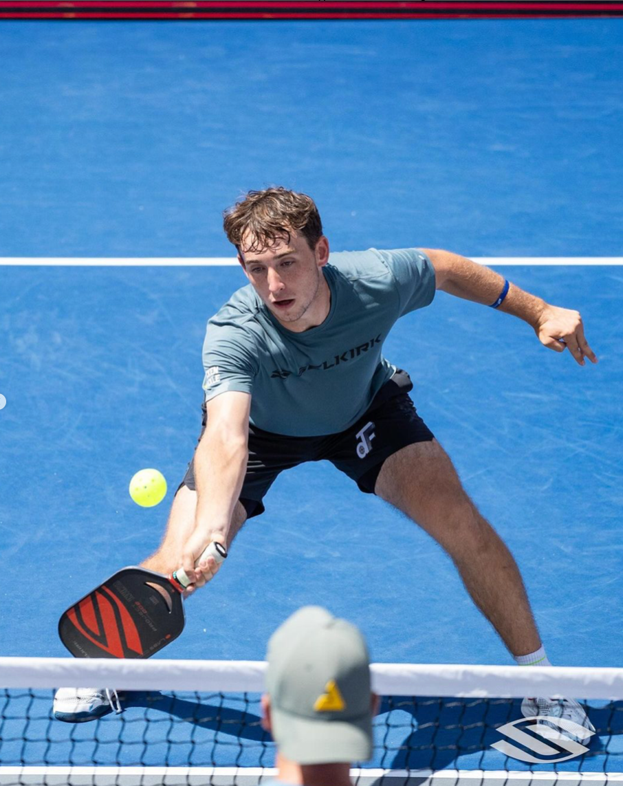 Dylan Frazier lunging for a shot during a match, with a ball in play.