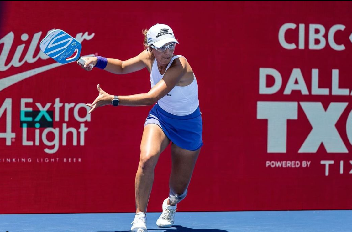 A female player hitting a pickleball during a match, with a red background featuring sponsor logos.