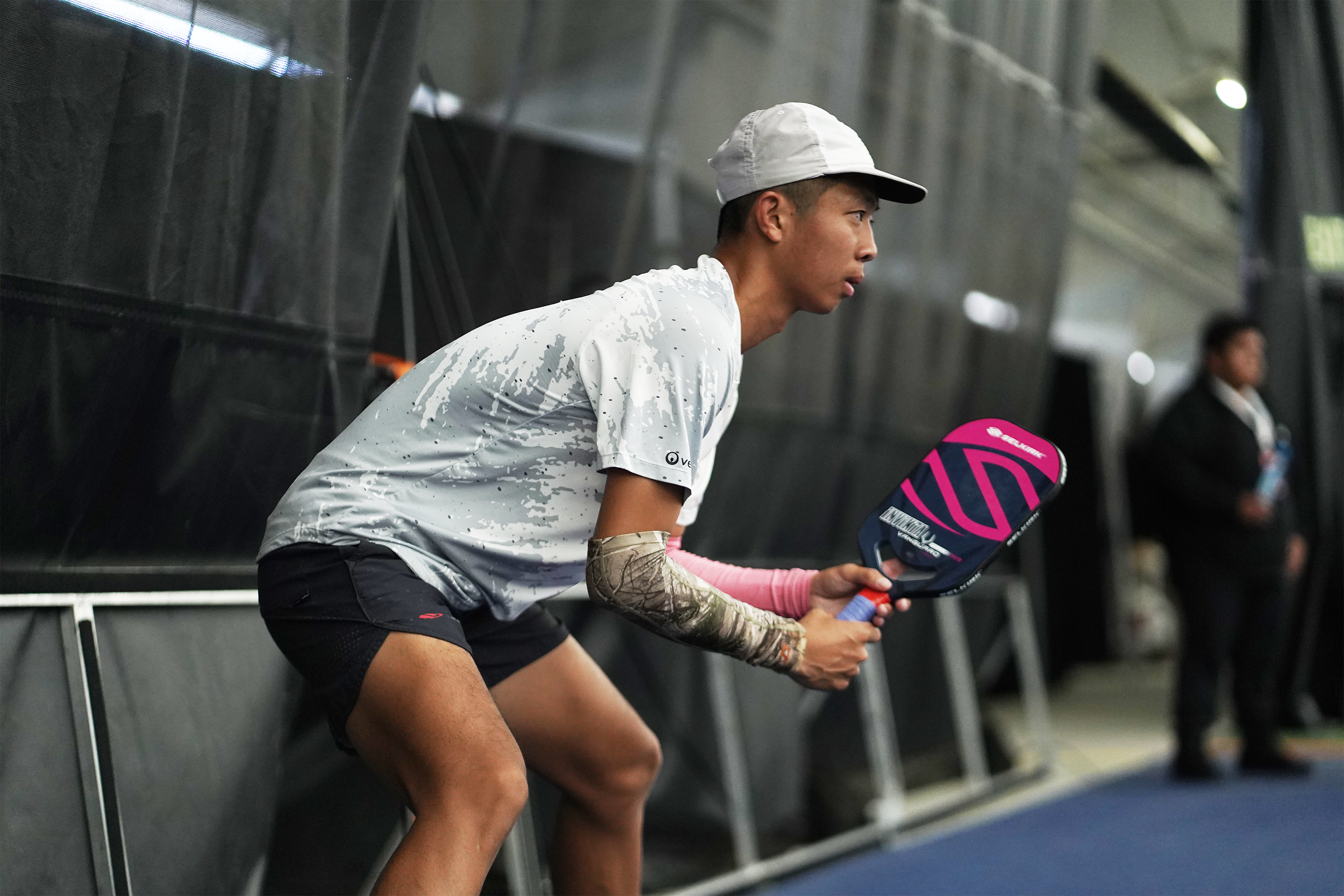 A young male player preparing to serve with a pickleball paddle in hand