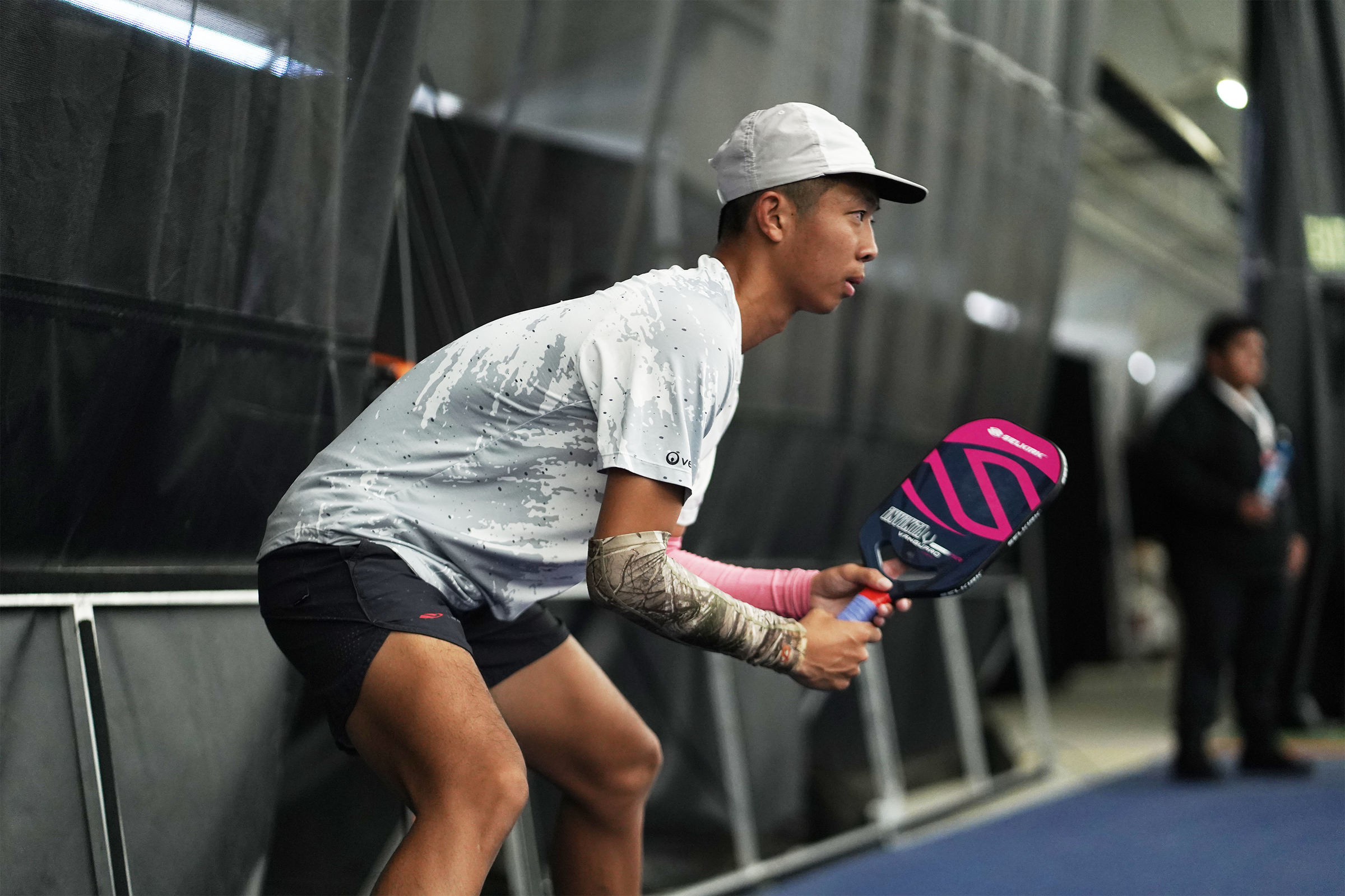 A young male player preparing to serve with a pickleball paddle in hand